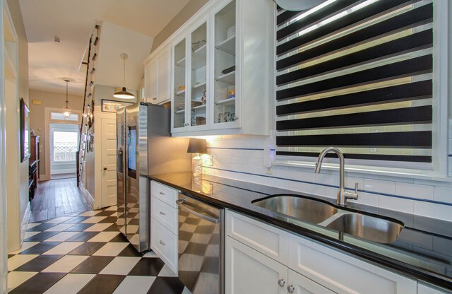 kitchen with tasteful backsplash, sink, stainless steel appliances, decorative light fixtures, and white cabinets