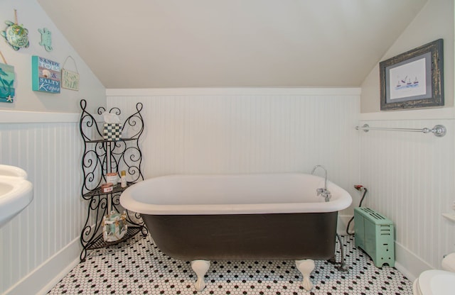 bathroom featuring a bathtub, toilet, lofted ceiling, and tile patterned flooring