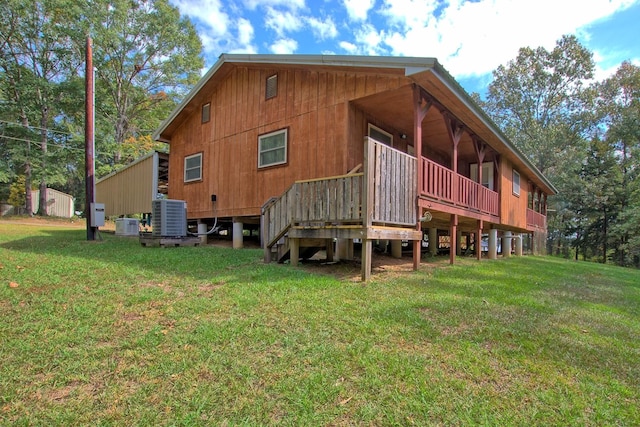 rear view of property with a lawn, central air condition unit, and a wooden deck