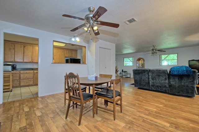 dining room with ceiling fan, light hardwood / wood-style flooring, and a textured ceiling