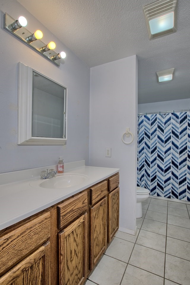 bathroom with vanity, tile patterned flooring, toilet, a textured ceiling, and walk in shower