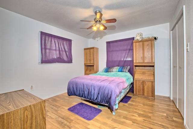 bedroom with ceiling fan, a textured ceiling, and light wood-type flooring