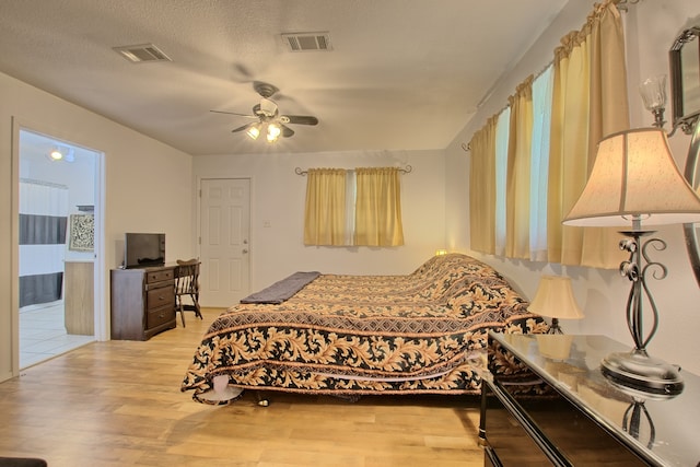 bedroom featuring ceiling fan, light hardwood / wood-style floors, and a textured ceiling