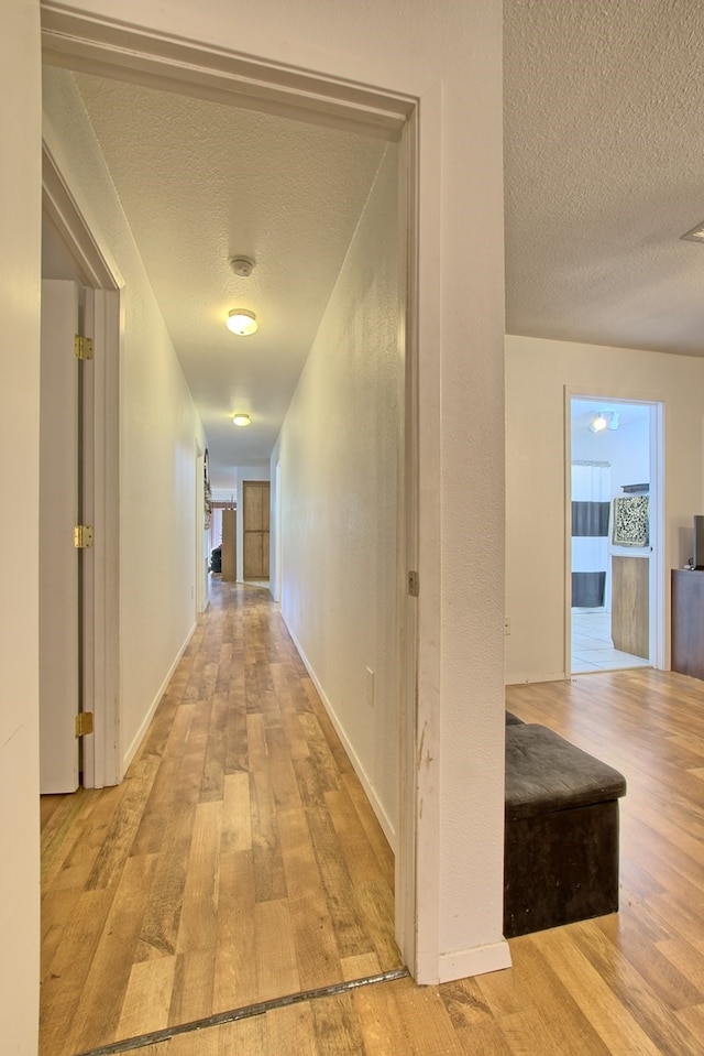 hall featuring a textured ceiling and light hardwood / wood-style flooring