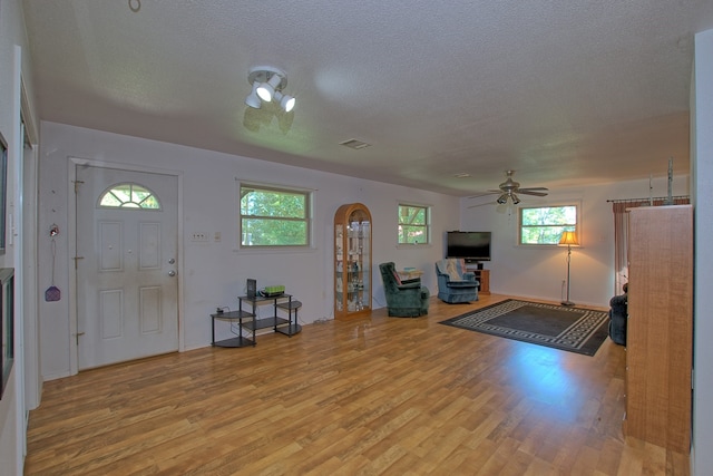 foyer with a textured ceiling, light wood-type flooring, and ceiling fan