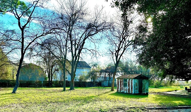 view of yard featuring a storage shed, fence, and an outbuilding