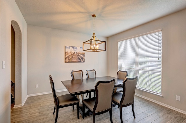 dining area with light hardwood / wood-style floors, a textured ceiling, and a chandelier