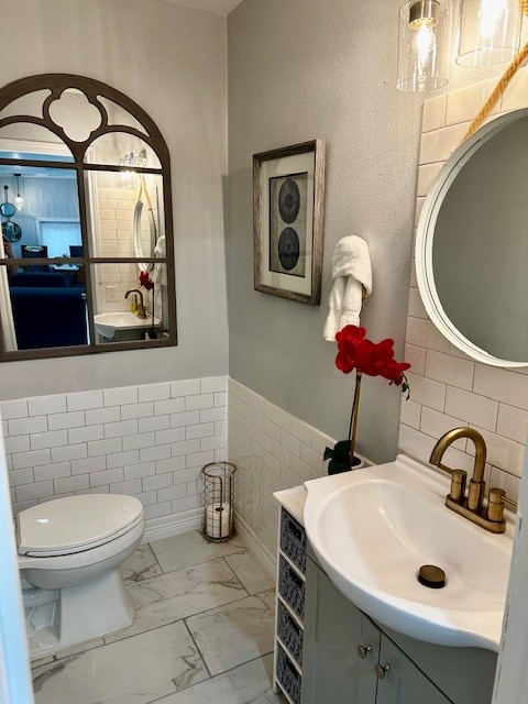 bathroom featuring tile walls, vanity, and toilet