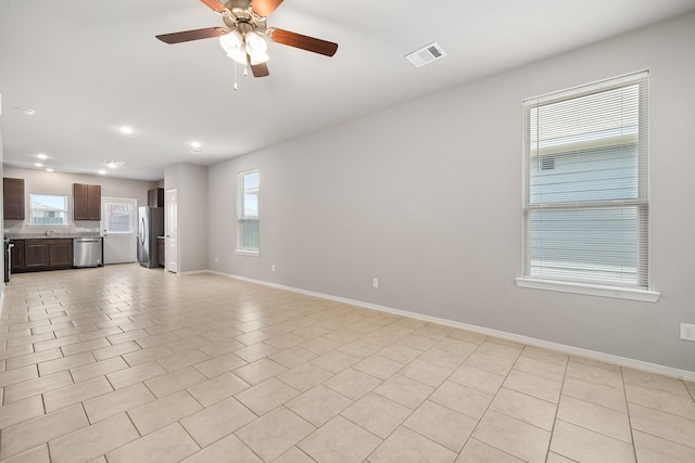 unfurnished living room featuring ceiling fan, light tile patterned floors, and plenty of natural light