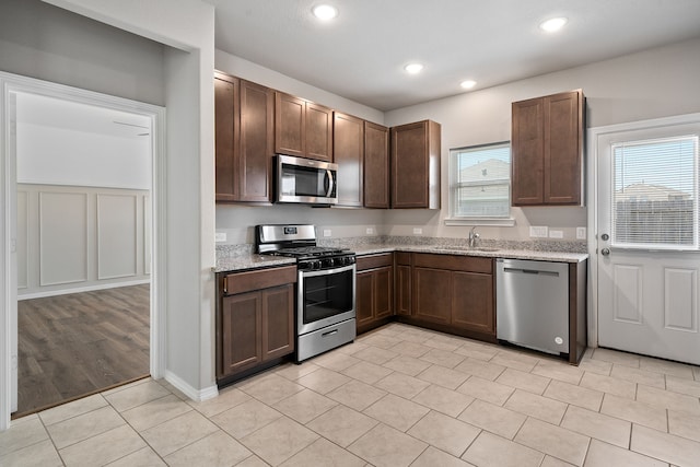 kitchen featuring a healthy amount of sunlight, stainless steel appliances, sink, and light stone counters