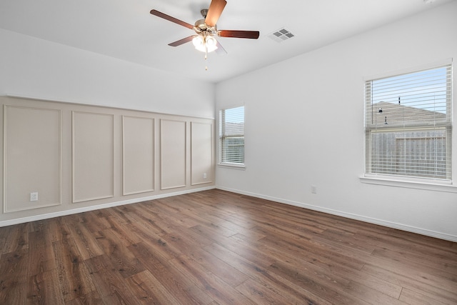 unfurnished room featuring ceiling fan, a healthy amount of sunlight, and dark hardwood / wood-style flooring