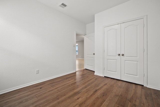 unfurnished bedroom with a closet and dark hardwood / wood-style flooring