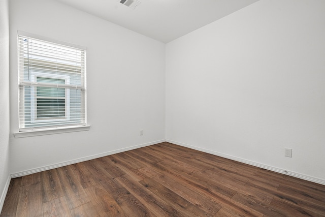 spare room featuring a wealth of natural light and dark hardwood / wood-style floors