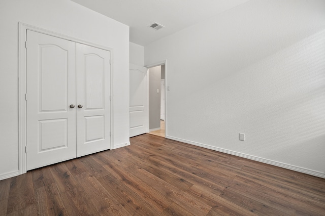 unfurnished bedroom with dark wood-type flooring and a closet