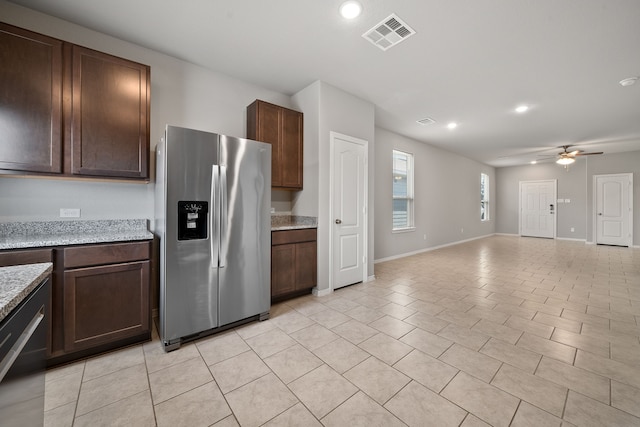 kitchen with dark brown cabinetry, light stone counters, stainless steel refrigerator with ice dispenser, and ceiling fan