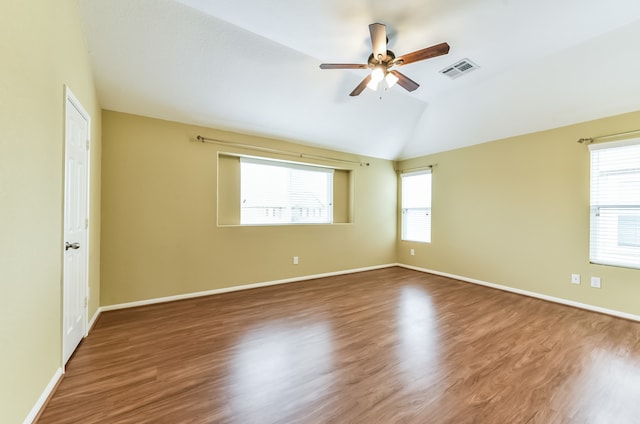 spare room with a healthy amount of sunlight, vaulted ceiling, and dark hardwood / wood-style floors