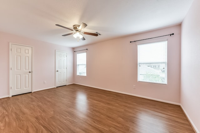 unfurnished bedroom with ceiling fan, hardwood / wood-style flooring, and multiple windows