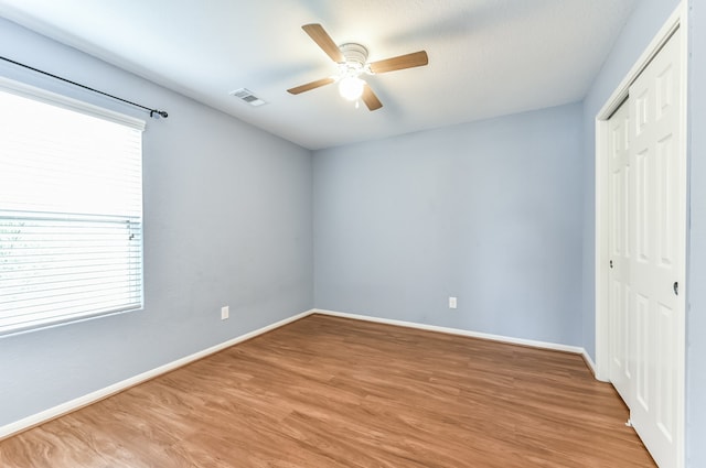 unfurnished bedroom featuring hardwood / wood-style floors, a closet, and ceiling fan