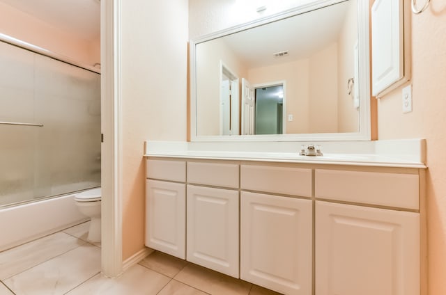 full bathroom with vanity, toilet, tile patterned floors, and bath / shower combo with glass door