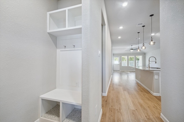 mudroom with ceiling fan, sink, and light wood-type flooring