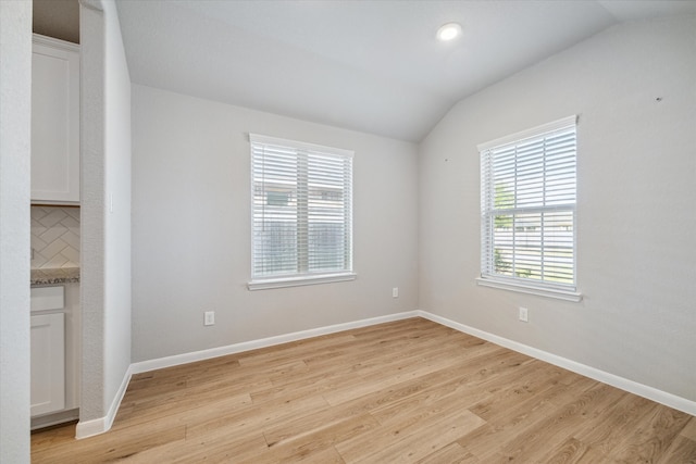 unfurnished room featuring lofted ceiling and light wood-type flooring