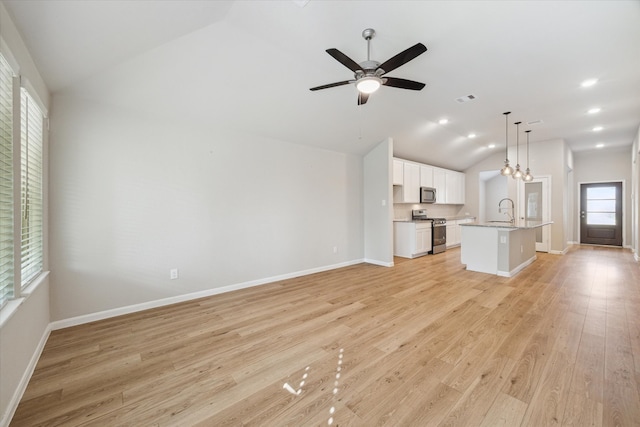 unfurnished living room featuring sink, lofted ceiling, light wood-type flooring, and ceiling fan with notable chandelier