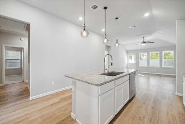 kitchen featuring sink, light wood-type flooring, white cabinetry, light stone counters, and a kitchen island with sink