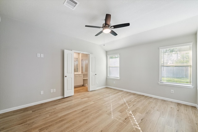 unfurnished bedroom with light hardwood / wood-style flooring, multiple windows, connected bathroom, and ceiling fan