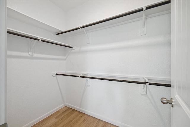 walk in closet with light hardwood / wood-style floors