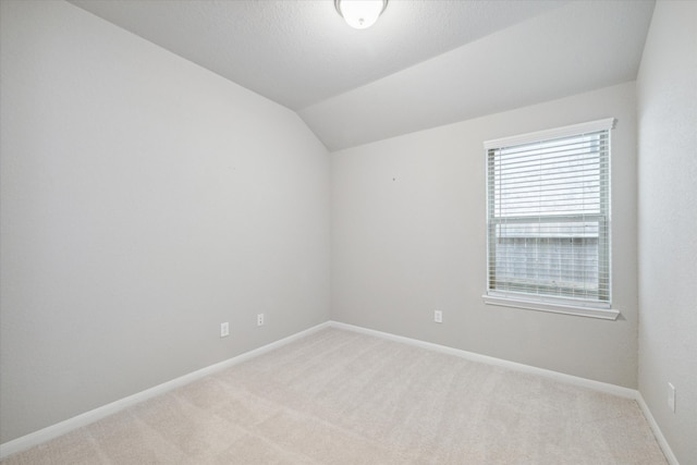 unfurnished room with lofted ceiling and light colored carpet