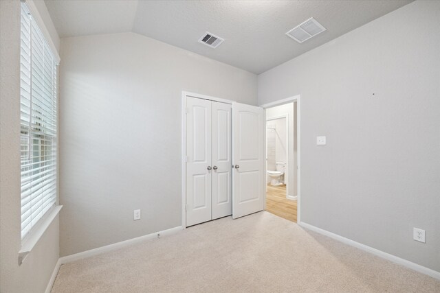 unfurnished bedroom with a closet, light carpet, and vaulted ceiling