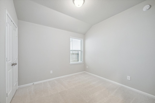 carpeted empty room with lofted ceiling