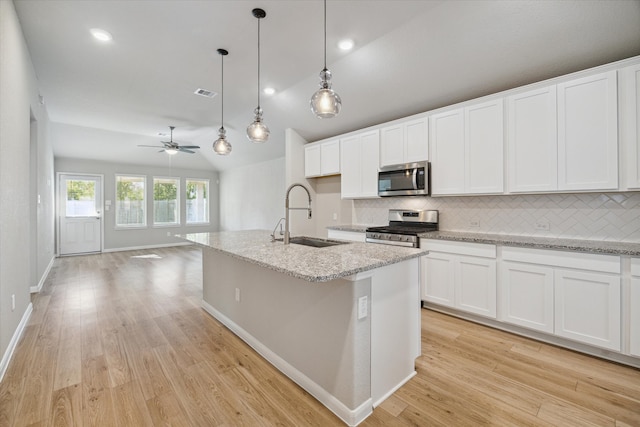 kitchen featuring sink, white cabinetry, stainless steel appliances, pendant lighting, and a kitchen island with sink