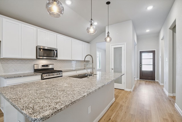 kitchen with appliances with stainless steel finishes, sink, light wood-type flooring, an island with sink, and white cabinets