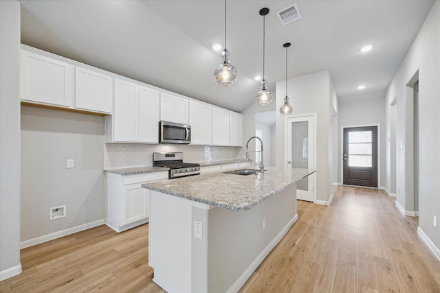 kitchen featuring a kitchen island with sink, hanging light fixtures, sink, white cabinetry, and appliances with stainless steel finishes