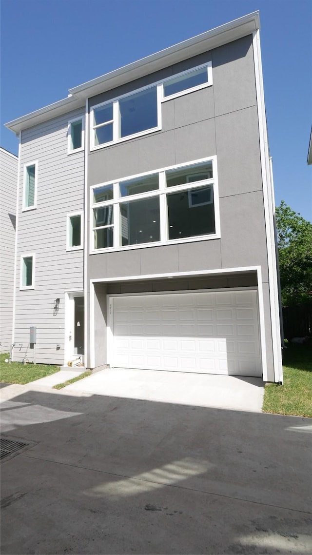 view of front facade featuring an attached garage, driveway, and stucco siding