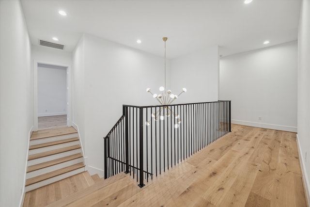 corridor featuring light hardwood / wood-style flooring and an inviting chandelier