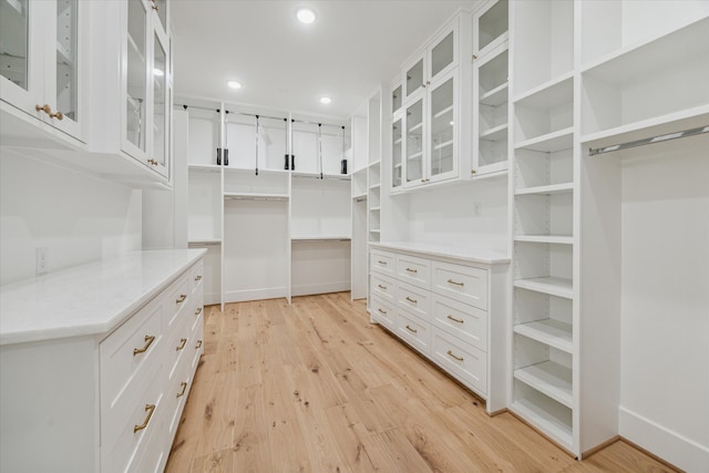 walk in closet with light hardwood / wood-style floors