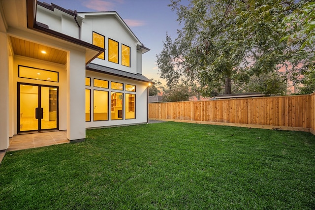 back house at dusk featuring a yard