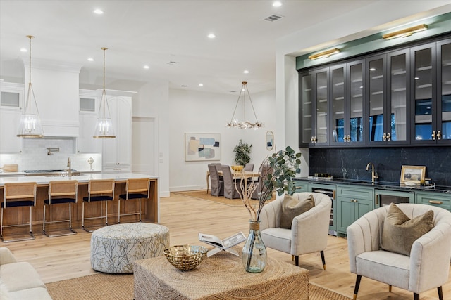 living room with light hardwood / wood-style flooring, beverage cooler, and sink