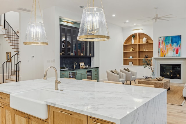 kitchen featuring light brown cabinetry, built in features, decorative light fixtures, and sink