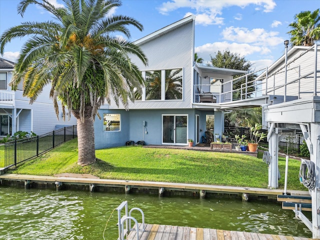 rear view of property with a lawn, a water view, and a balcony