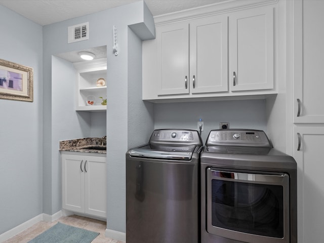 clothes washing area featuring cabinets, a textured ceiling, sink, and independent washer and dryer