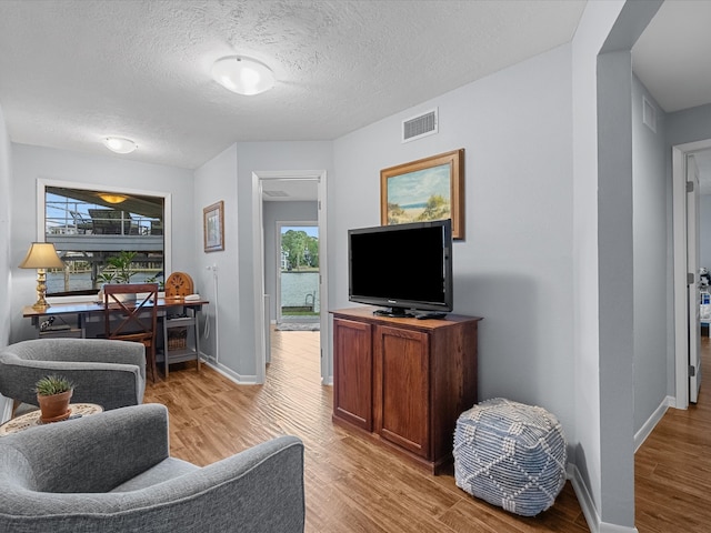 living room with light hardwood / wood-style floors and a textured ceiling