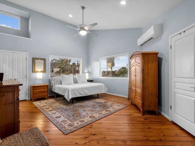 bedroom with a wall mounted AC, light hardwood / wood-style flooring, multiple windows, and ceiling fan