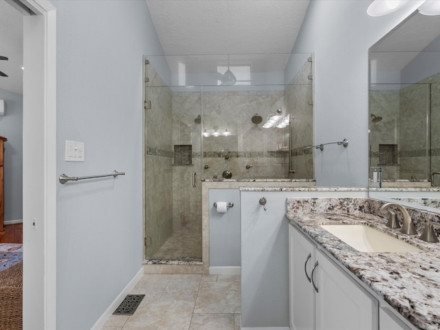 bathroom with vanity, a textured ceiling, tile patterned floors, and a shower with shower door