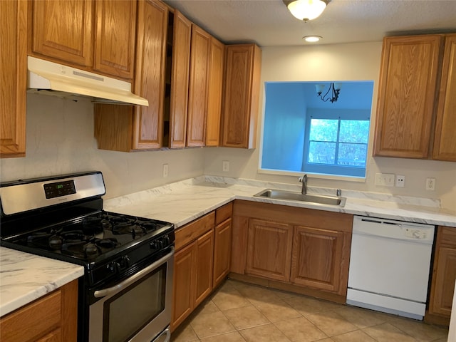 kitchen with dishwasher, gas range, sink, light tile patterned flooring, and an inviting chandelier