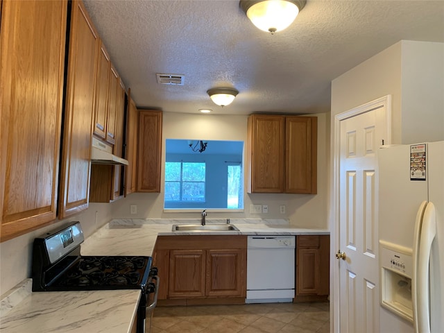 kitchen featuring white appliances, light tile patterned floors, a textured ceiling, and sink