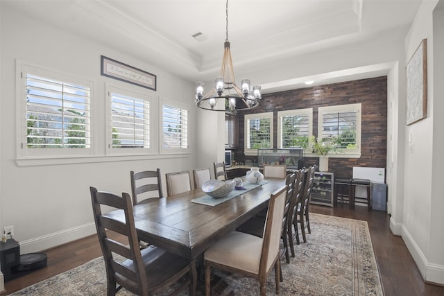 dining room featuring a wealth of natural light, a raised ceiling, a notable chandelier, and dark hardwood / wood-style flooring