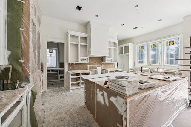 kitchen featuring white cabinetry, a center island, backsplash, and a wealth of natural light